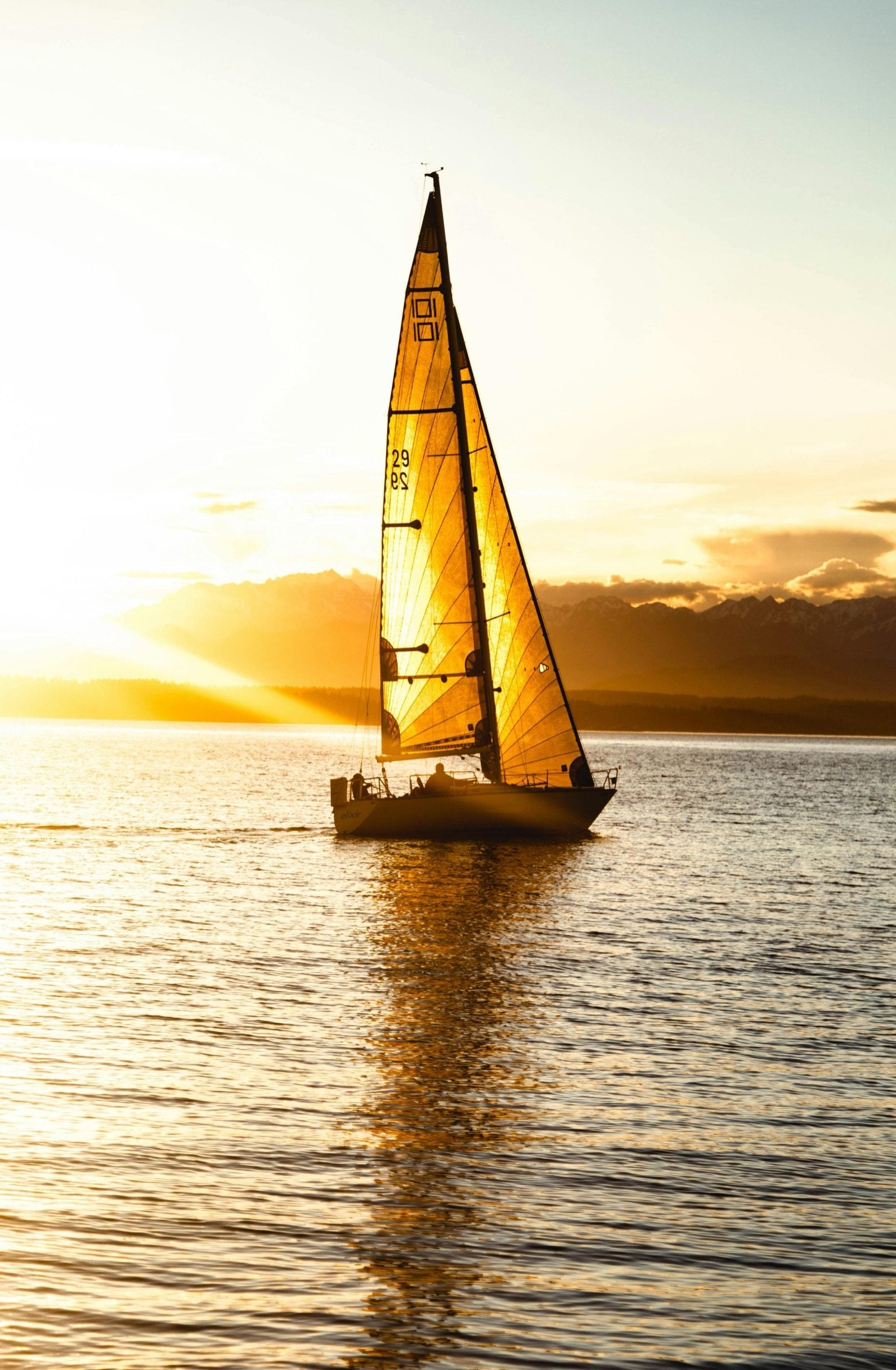 Sailboat lit by golden hour on the Tagus, sail glowing against the sun
