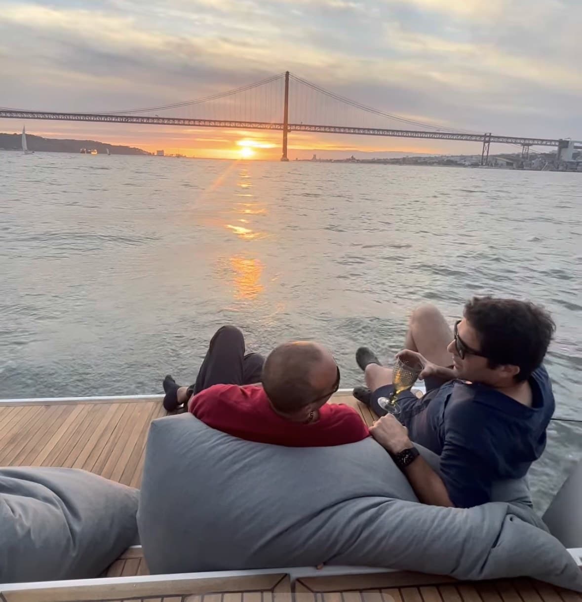 Friends sharing a meal in the cockpit at sunset, Padrão dos Descobrimentos in the distance