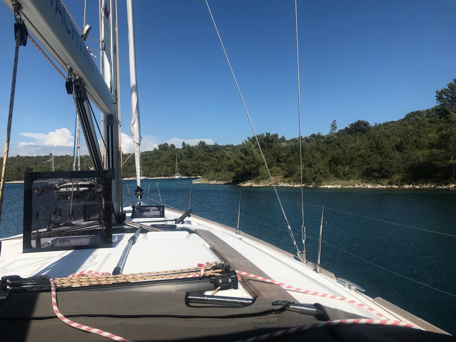 The Bavaria at anchor in a quiet pine-lined bay