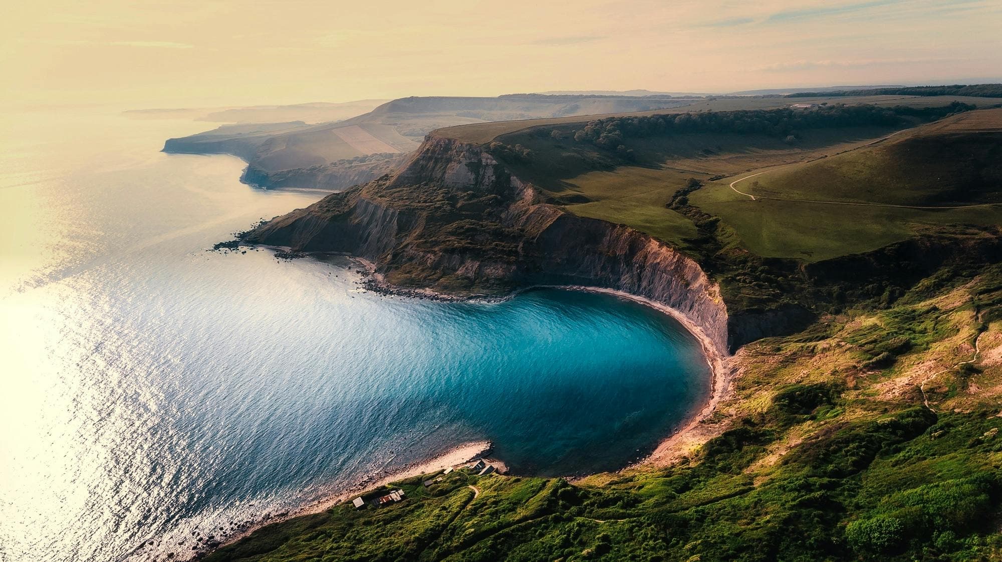 Coastal cliffs falling into a turquoise cove, drone view